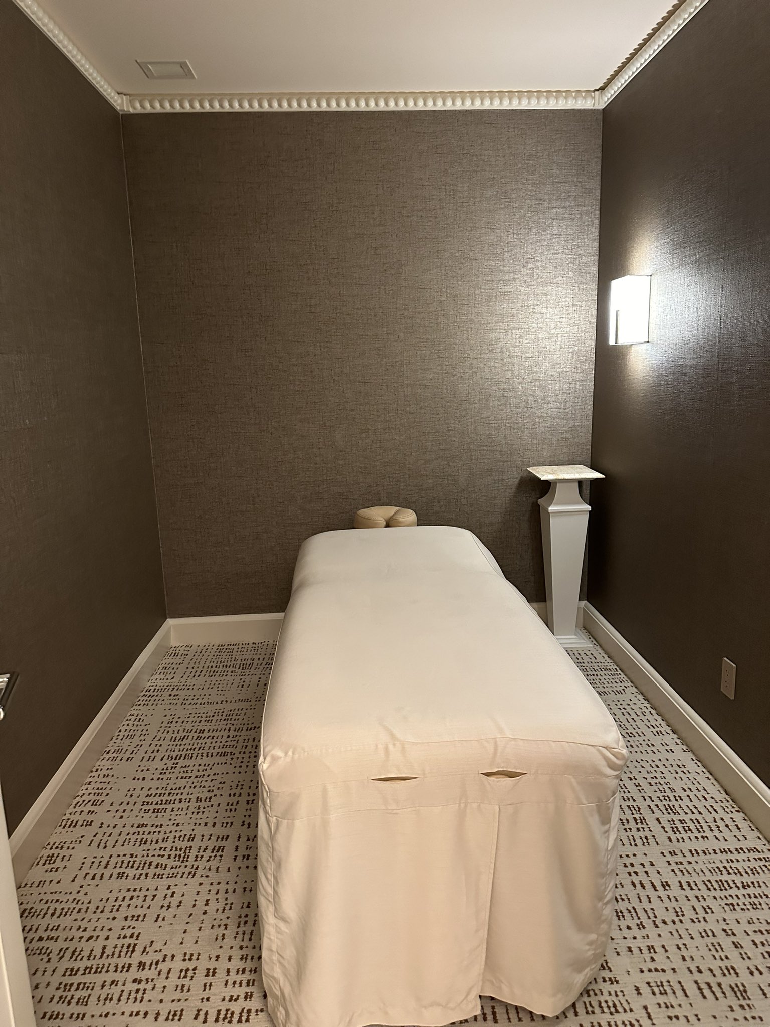 A calm private treatment room with a dressed massage table